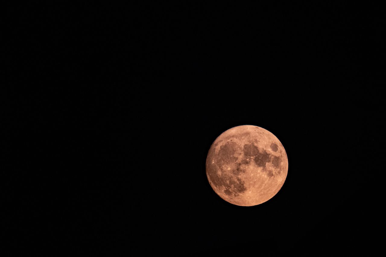 A stunning red full moon glowing brightly in the night sky.